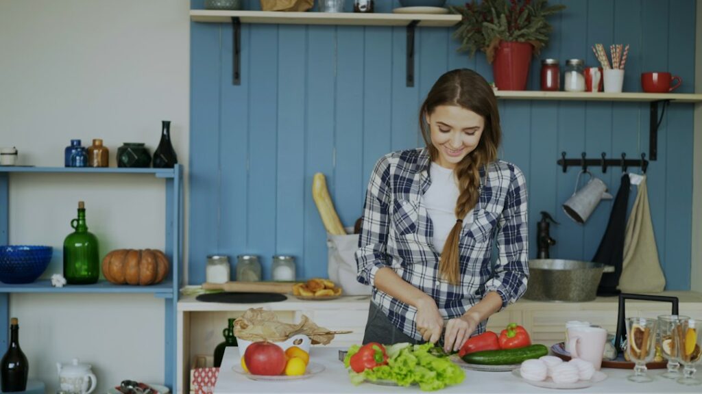 Adult preparing a balanced plate with vegetables, protein, whole grains, and a glass of water in a home kitchen.